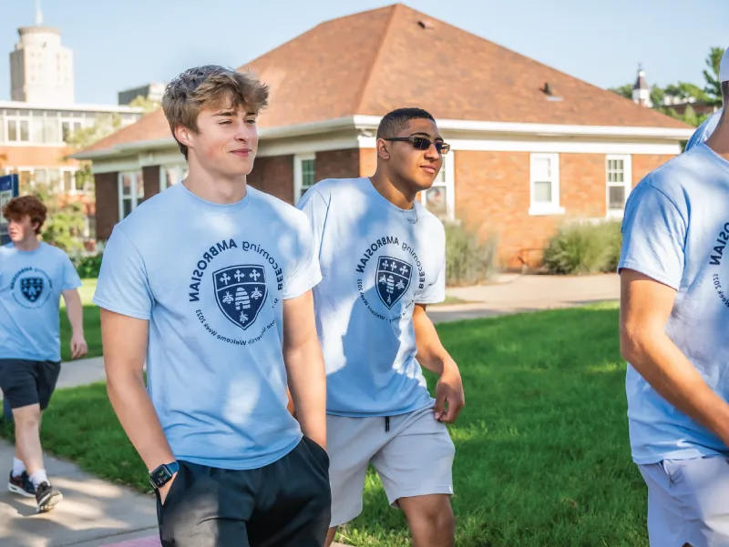 Two students walking outdoors wearing shirts reading 